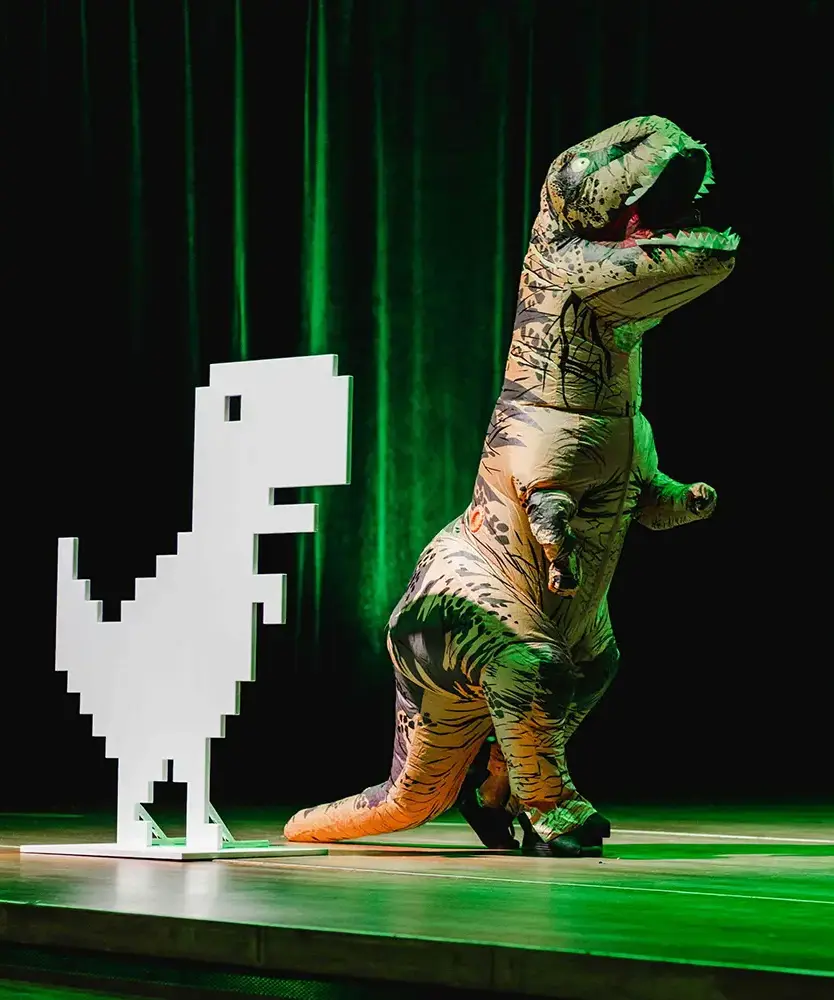 Osoba w przebraniu dinozaura występuje na scenie konferencyjnej.